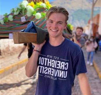 瑞安伯格 smiling on procession with fellow students and wearing Creighton t-shirt.